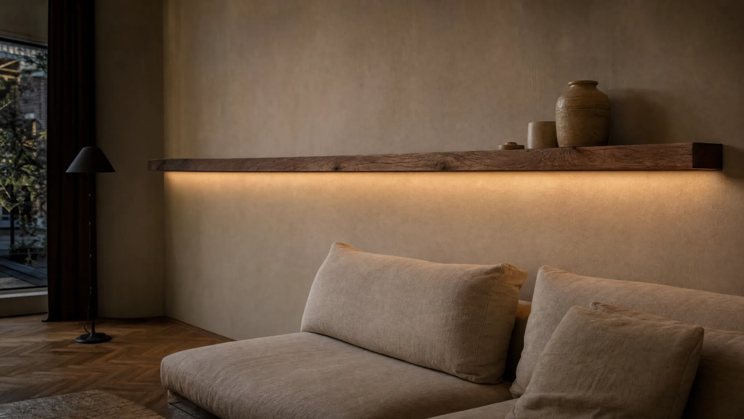 Lange eiken wandplank met warm LED-licht boven een linnen bank